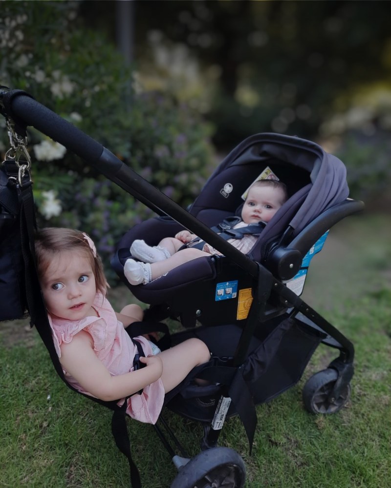 Hamaca Pepe Pillo en un jardín: bebé en huevo y hermana mayor sentada, paseando juntos